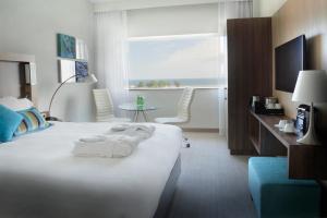 a hotel room with a large white bed and a window at Courtyard by Marriott Gdynia Waterfront in Gdynia