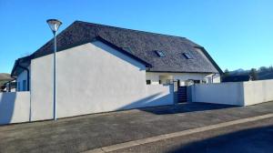 una casa blanca con una pared blanca y una luz de la calle en Chambres d'hôtes les Hirondelles, en Lanne-en-Barétous 