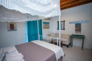 a bedroom with a canopy bed and a couch at Patmos Houses Tennis & Beach Tennis Court's in Patmos