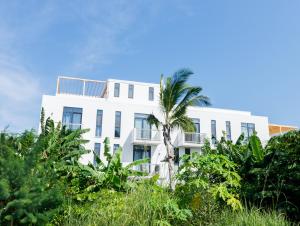 a white building with a palm tree in front of it at Lovely one-bed with pool and beach access in Paje, Zanzibar! in Paje