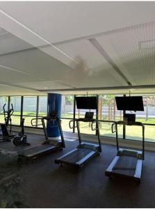 a gym with several tread machines and a large window at Blue Beach pé na areia, Resort e praia in Cabedelo