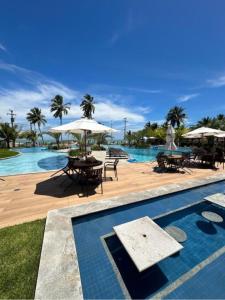 uma piscina com mesas e guarda-sóis num resort em Blue Beach pé na areia, Resort e praia em Cabedelo