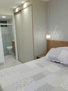 a bedroom with a white bed and a bathroom at Blue Beach pé na areia, Resort e praia in Cabedelo