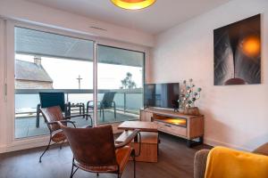 un salon avec une télévision, une table et des chaises dans l'établissement La Proue - Charmant appt vue mer, à Concarneau