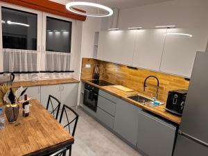 eine Küche mit weißen Schränken und einem Holztisch in der Unterkunft Aparthotel Zabrze, Apartament Agnieszka in Zabrze