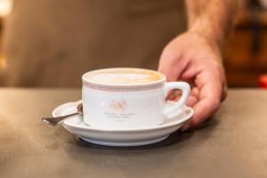 a person holding a cup of coffee on a table at Adler Cavalieri Hotel-Private Spa & Gym in Florence