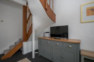 a tv on a dresser in a room with a staircase at 69DS · Cosy 4 Sleeper Central Windsor - Castle Theatre - Pass The Keys in Windsor