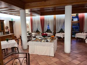 uma sala de jantar com mesas e cadeiras brancas e mesas e cadeiras brancas em Hotel Albergo Dolomiti em San Vito di Cadore