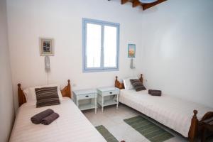 2 camas individuales en una habitación con ventana en Patmos Houses Tennis & Beach Tennis Court's, en Patmos