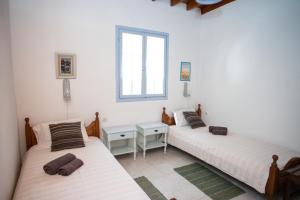 two twin beds in a room with a window at Patmos Houses Tennis & Beach Tennis Court's in Patmos