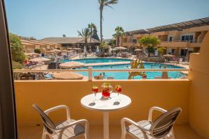 balcón con mesa, sillas y piscina en Hotel Arena Suite, en Corralejo