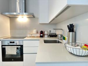 a kitchen with white cabinets and a sink and a stove at New Port, Free Parking YBH6A in Vigo