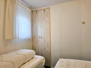 Zimmer mit 2 Betten, einem Schrank und einem Fenster in der Unterkunft Chalet Noelle SE14 in Serooskerke