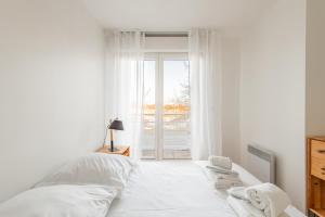 een witte slaapkamer met een bed en een raam bij Panhard - Cosy place proche Gare de Lyon in Parijs