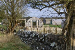 a log cabin with a fence and a stone wall at Beautiful couples retreat with hot tub, central heating and views- The Bee Hive by Get Better Getaways in Glenluce