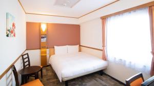 um pequeno quarto com uma cama e uma janela em Toyoko Inn Hokkaido Asahikawa Ekimae Ichijo dori em Asahikawa