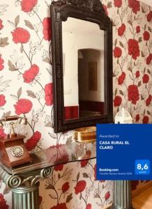 un espejo en una pared con flores rojas en CASA RURAL EL CLARO, en Torquemada