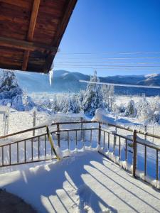 a porch covered in snow with a fence at Къща за гости Балканъ in Kyustendil