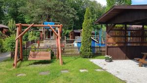 un parque infantil con un banco de madera en un patio en Domki Przy Lesie, en Stegna