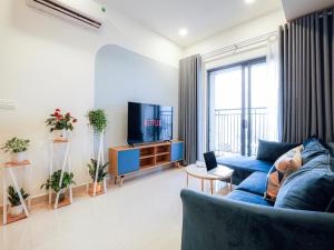 a living room with a blue couch and a tv at May Soho Saigon Serviced Apartment in Ho Chi Minh City