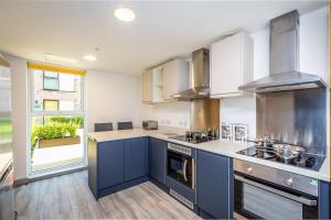 a large kitchen with blue cabinets and a window at Ensuite Room With Shared Kitchen, Close to Centre in Lincoln