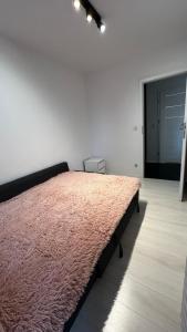 a bedroom with a large bed with a pink blanket at Nowe mieszkanie 4-osobowe z ogródkiem Kraków in Kraków