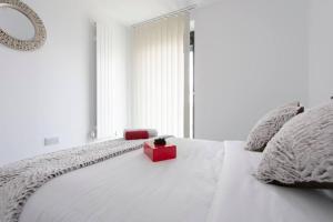 un letto bianco con una scatola rossa sopra di Utopian Modern Apartments a Londra