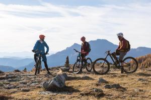 três pessoas a andar de bicicleta no topo de uma montanha em Hotel Tiefenbrunn Gardensuites & Breakfast em Lana