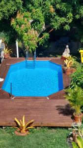 einen Pool auf einer Holzterrasse mit einem blauen Pool in der Unterkunft Studio La villa du manguier in Le Vauclin