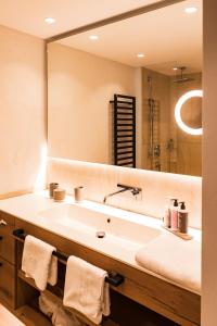 La salle de bains est pourvue d'un lavabo et d'un grand miroir. dans l'établissement Hotel Sonnenhof, à Grän