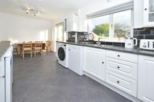 a white kitchen with a washer and dryer in it at Sweetbriar House - By Sigma Stays in Crewe