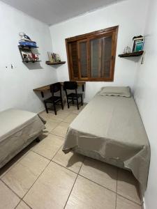 a bedroom with a bed and a table and chairs at Legítima casa de praia in Capão da Canoa