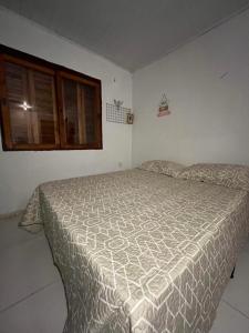 a bedroom with a bed with a comforter on it at Legítima casa de praia in Capão da Canoa