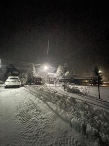 una calle cubierta de nieve por la noche con un coche aparcado en Beregynia, en Zhdeniievo