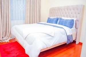 ein weißes Bett mit blauen Kissen und einem roten Teppich in der Unterkunft Wonderstay in Nairobi