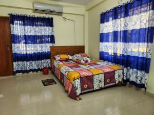 a bedroom with a bed and blue and white curtains at Aaira Manjil Guest House in Dhaka