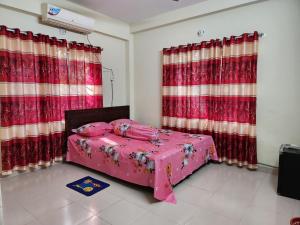 a bedroom with a pink bed with red curtains at Aaira Manjil Guest House in Dhaka
