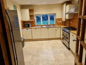 a kitchen with white cabinets and a stove top oven at Maryland Cottage Nr Gatwick in Godstone
