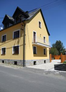 une maison jaune sur le côté d'une rue dans l'établissement U líného jezevce, à Abertamy