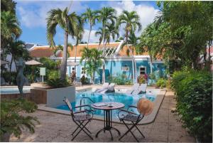 a patio with a table and chairs next to a pool at Kura Botanica Hotel in Willemstad