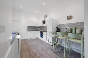 una cocina con armarios blancos y taburetes de bar en Cozy Home in Avenue Terrace, Sleeps 8, en Sunderland