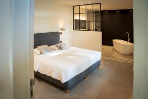 Schlafzimmer mit einem Bett und einer Badewanne in der Unterkunft Den Yzer in Oostvleteren
