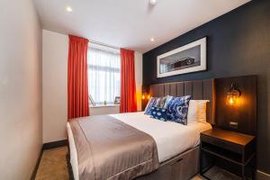 a bedroom with a large bed with red curtains at Duke Street Townhouse in Liverpool
