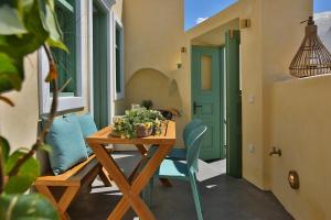 a patio with a wooden table and chairs and a green door at Yellow Orchid Cycladic House in Pyrgos