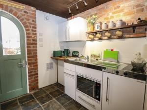 a kitchen with white cabinets and a green door at The Annexe in Fakenham