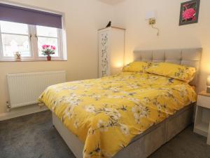 a bedroom with a yellow bed with yellow sheets and a window at The Annexe in Fakenham