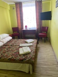 una camera d'albergo con letto, scrivania e finestra di Готель Клен a Rava-Rusʼka