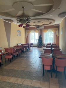 una sala da pranzo con tavoli, sedie e un albero di Natale di Готель Клен a Rava-Rusʼka