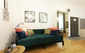a living room with a green couch with colorful pillows at 19Rooms in Krakow