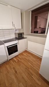 a kitchen with white appliances and a wooden floor at Mysigt Stadsoas: En Modern lägenhet med 2 sovrum in Gothenburg